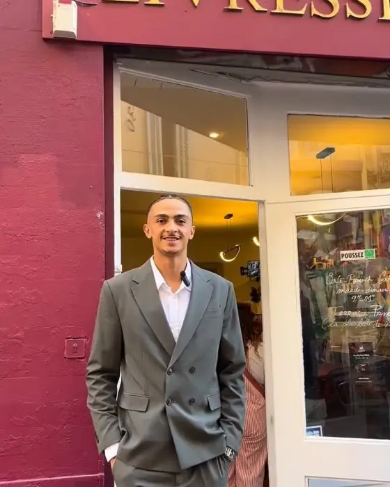 Une personne devant la façade bordeaux, porte ouverte sur la librairie.