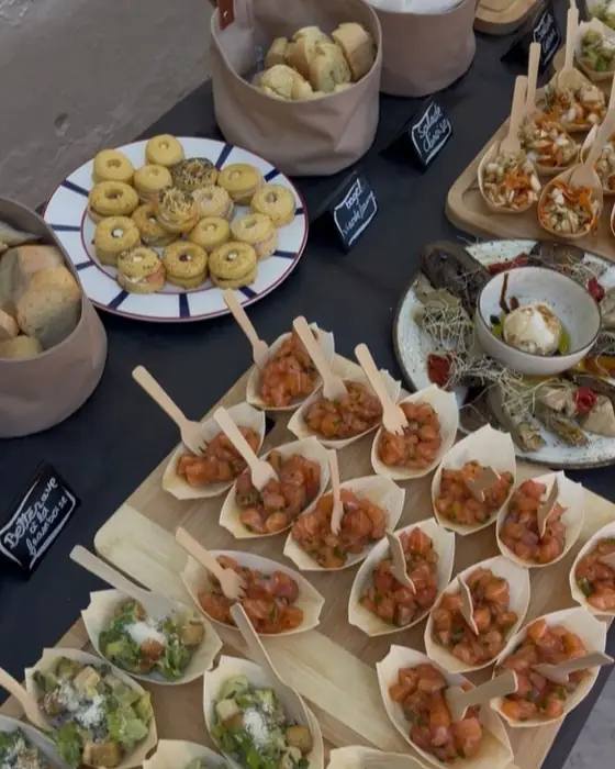 Buffet dressé: cornets de tartare, petites tartes et corbeilles de pain sur la table d'ardoise.