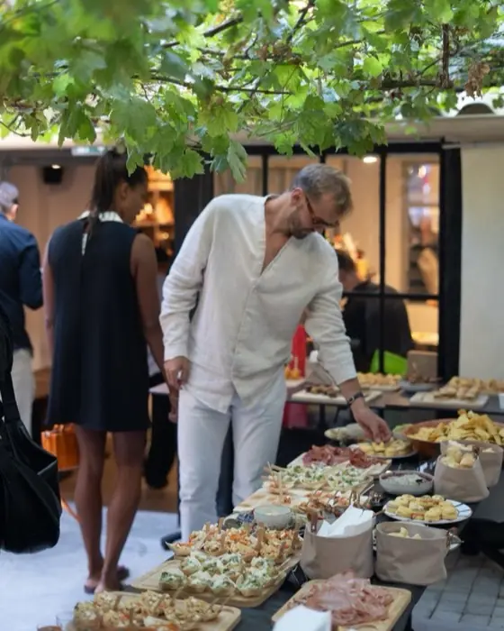 Invités autour du buffet sous les branches, en soirée.