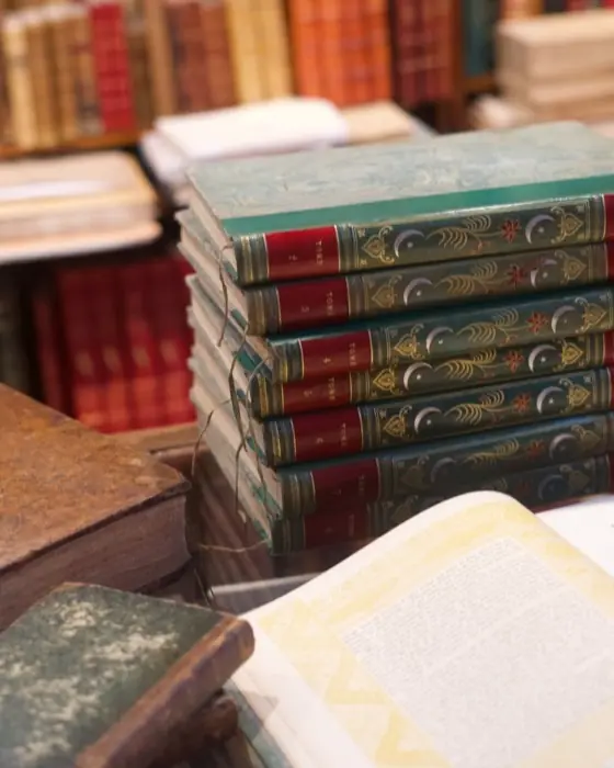 Pile de livres anciens reliés, à côté d'un ouvrage ouvert.