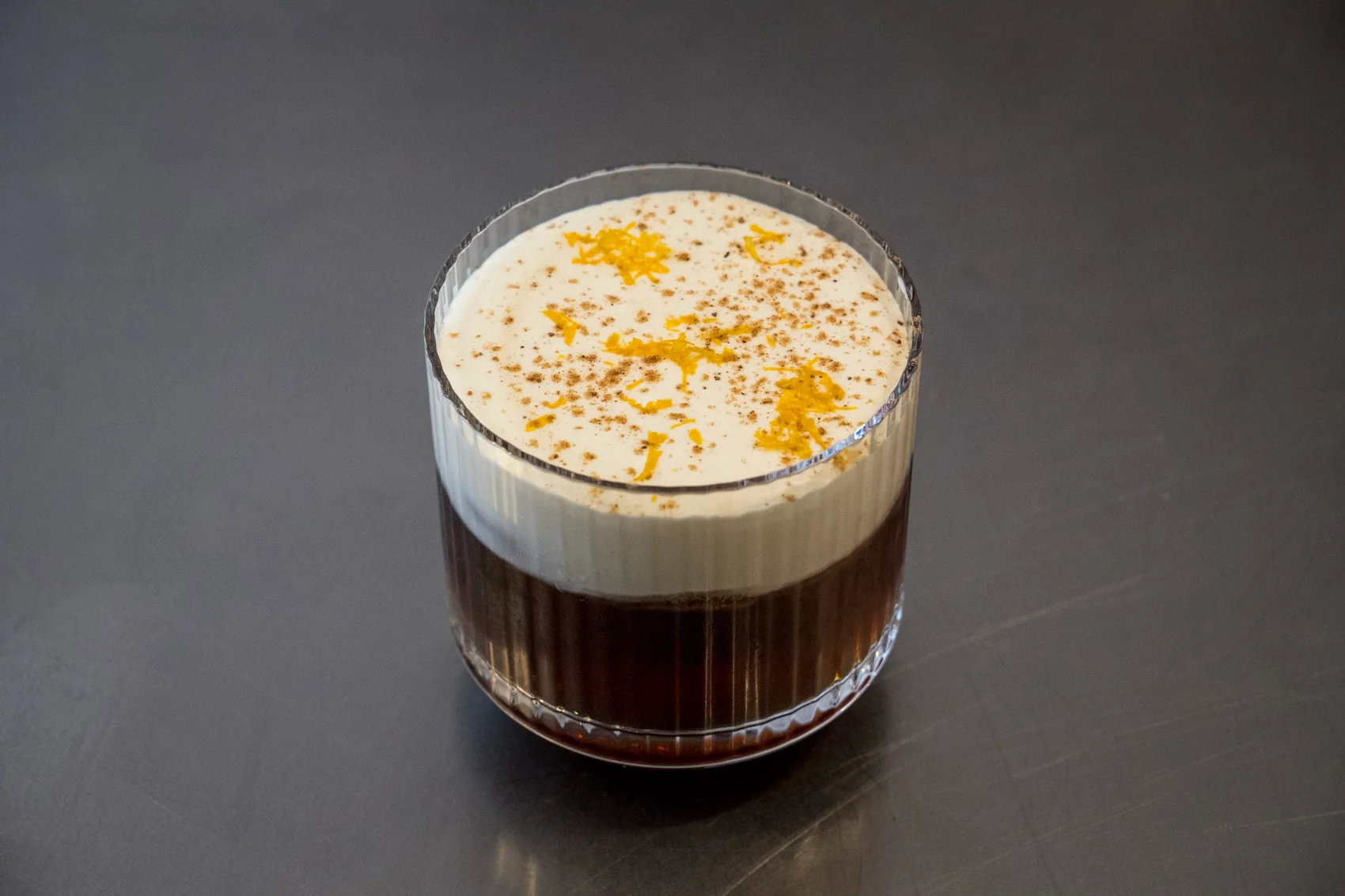 Boisson brune surmontée de mousse dans un verre, au comptoir