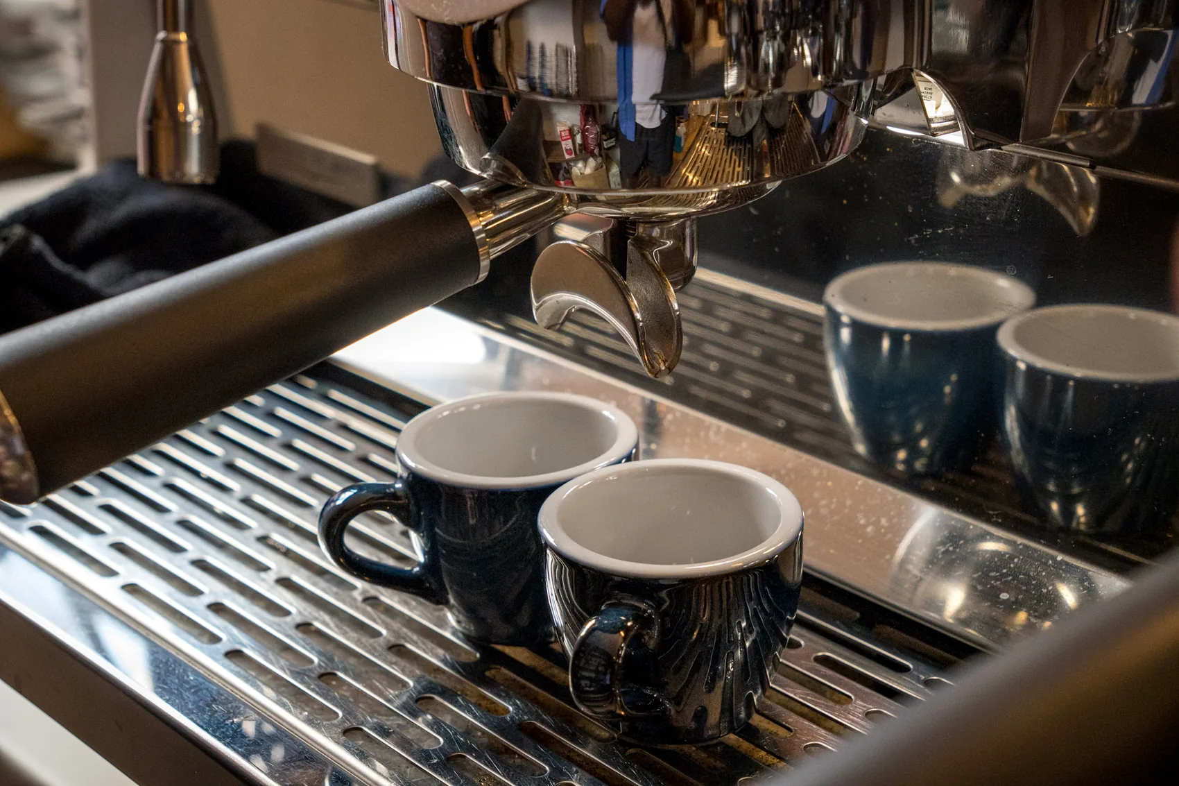 Machine espresso, porte-filtre et tasses disposées au comptoir