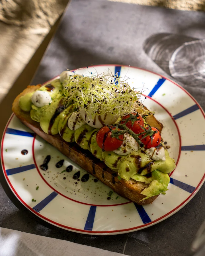 Tartine garnie sur une assiette rayée, à une table en terrasse