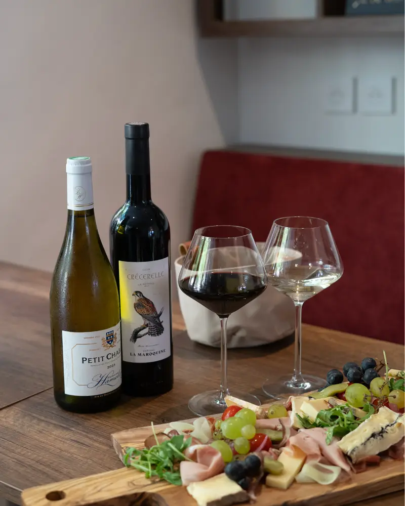 Bouteilles de vin, verres et planche de charcuterie dressés sur la table en bois